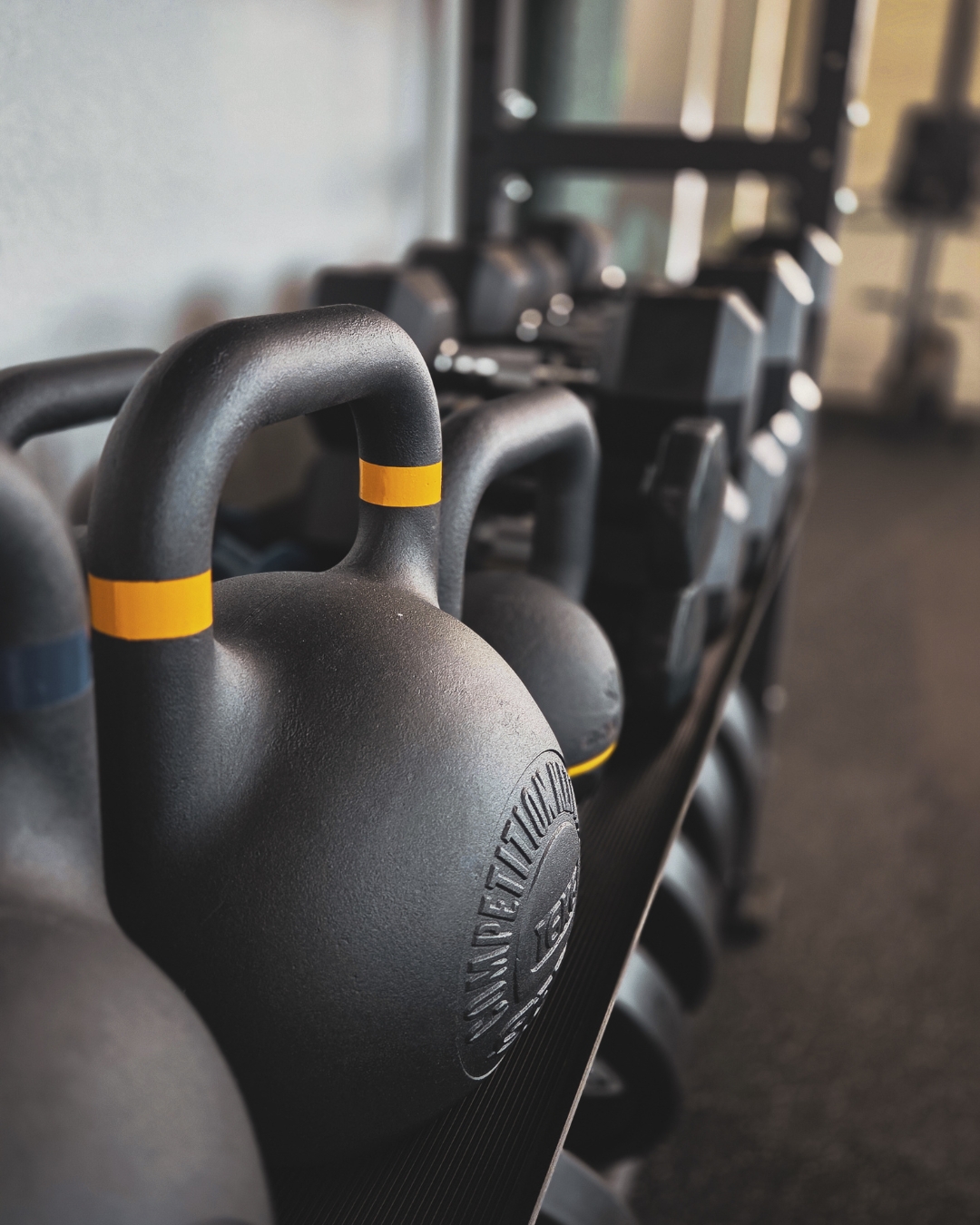 Kettlebells alignés dans une salle de sport, matériel utilisé en functional training chez Joy N Sport